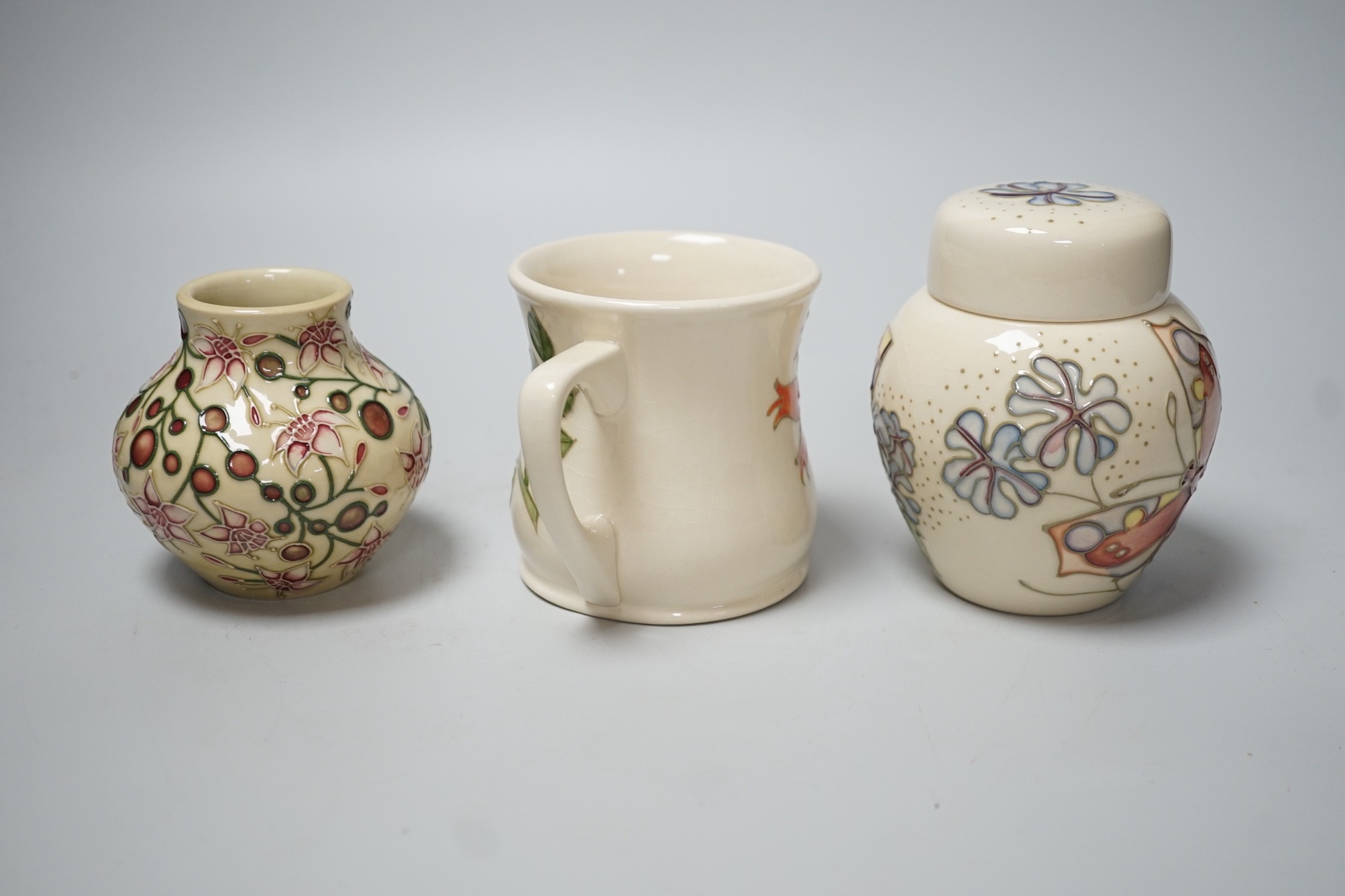 Three boxed Moorcroft pieces; Rose Hip cup, Butterfly jar and cover, and a Fuchsia vase, tallest 11 cm